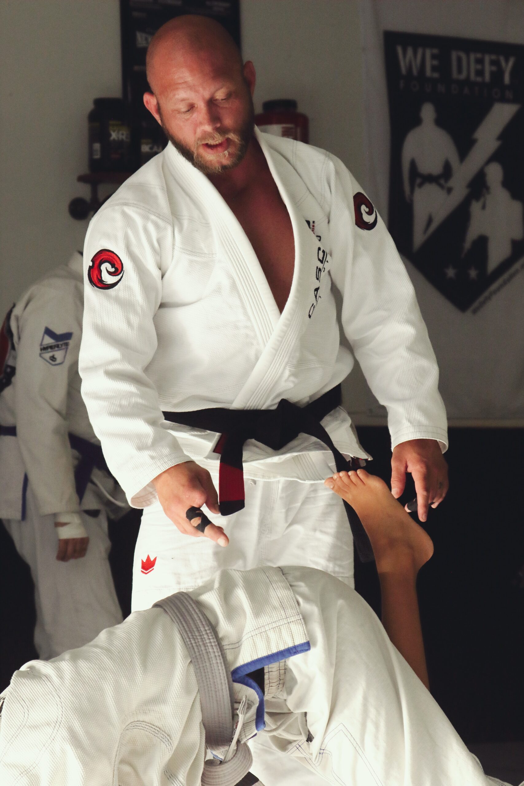 En Brasiliamsk jui jitsu instruktør med sort bælte, hjælper sine elever med at udføre en teknik.